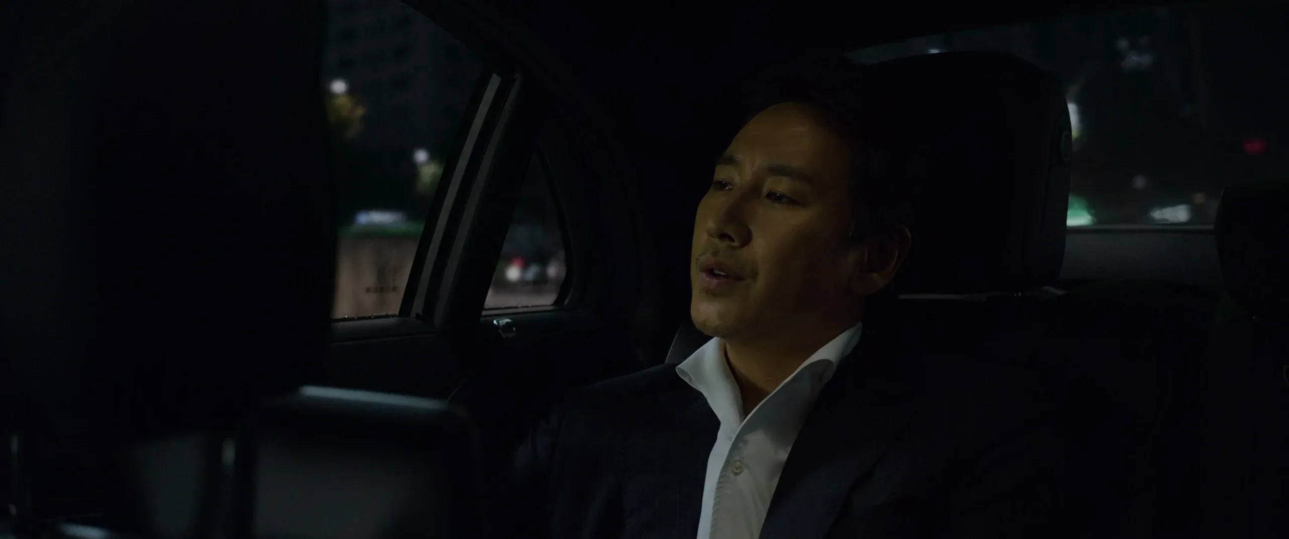 Mr. Park in the back seat, speaking about the line, with the front seat forming a barrier in the foreground.