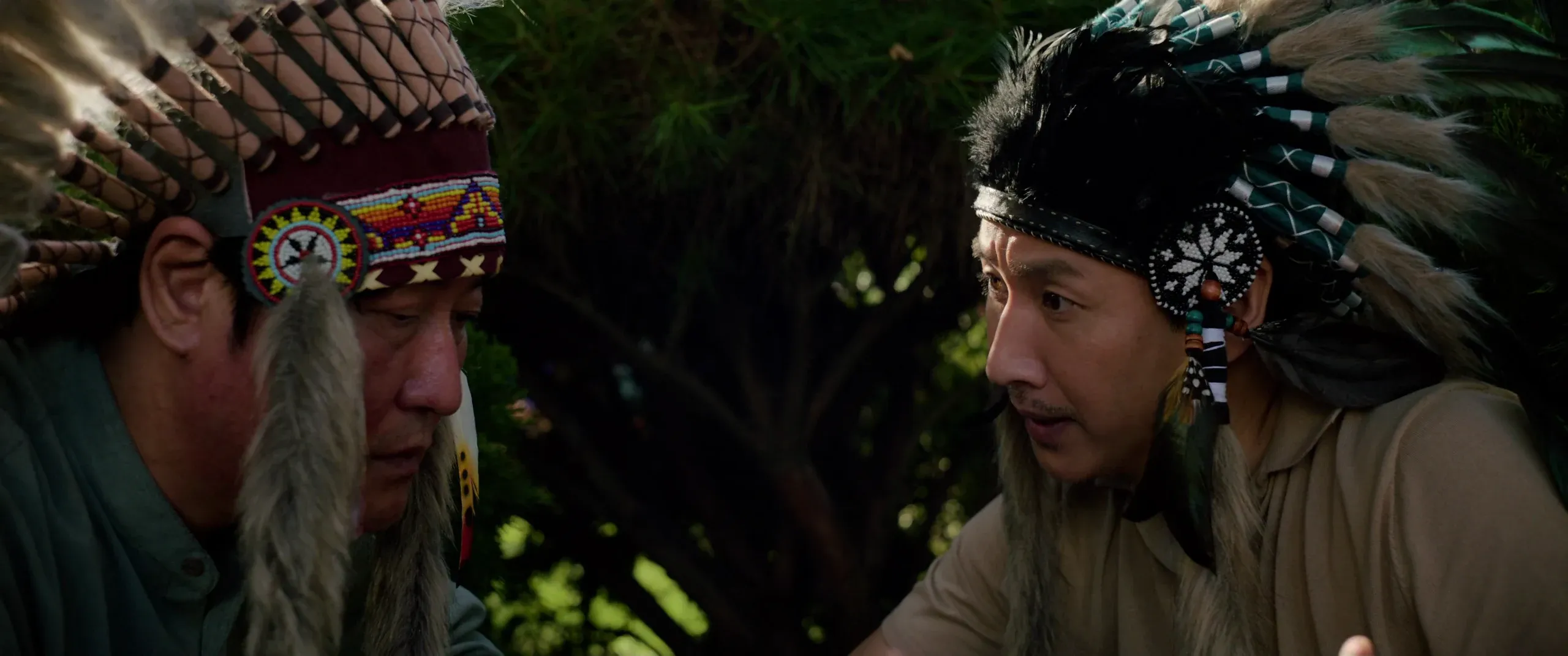 Mr. Park and Ki-taek in feathered headdresses at the party