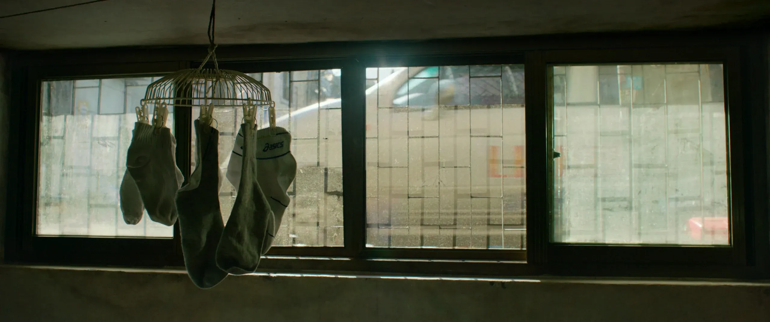 Daylight falling through the socks hung in the semi-basement window