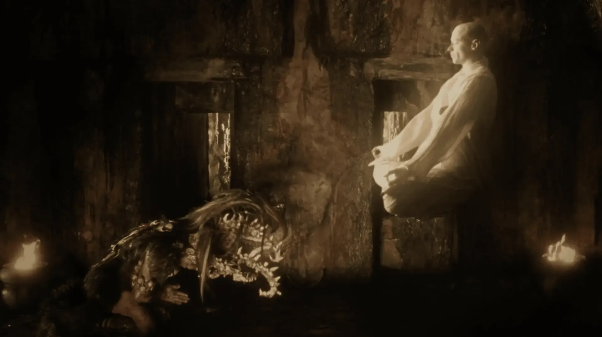 The bald traveler floats in meditation in a gold glow while the Maya priest kneels before him.