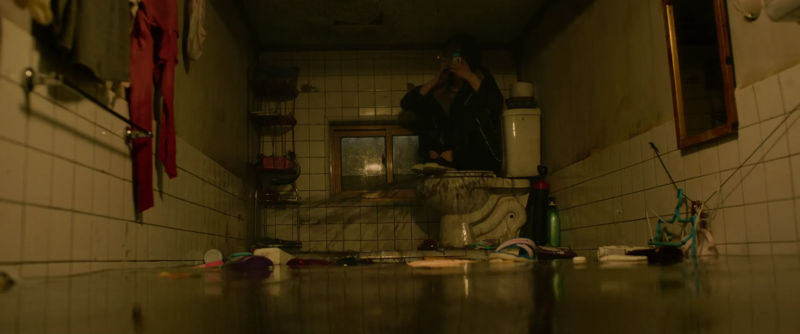 Ki-jung sitting on the lid of the erupting toilet, smoking